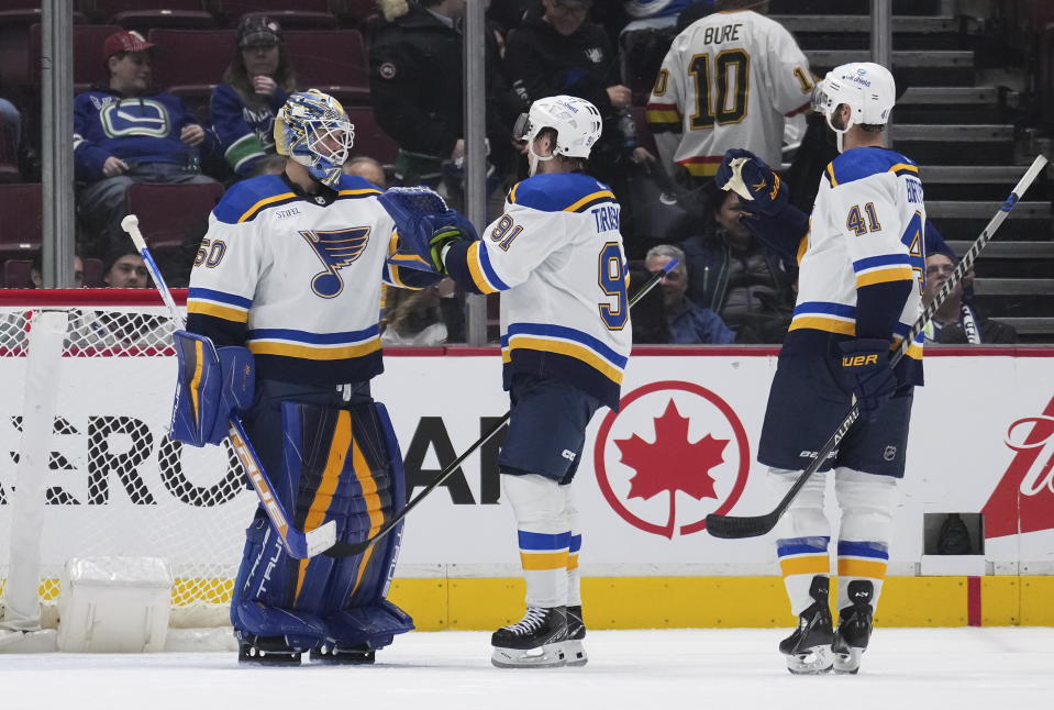 St. Louis Blues goalie Jordan Binnington, from left to right, Vladimir Tarasenko, of Russia, and Robert Bortuzzo celebrate after St. Louis defeated the Vancouver Canucks 5-1 during an NHL hockey game in Vancouver, British Columbia, on Monday, Dec. 19, 2022. (Darryl Dyck/The Canadian Press via AP)