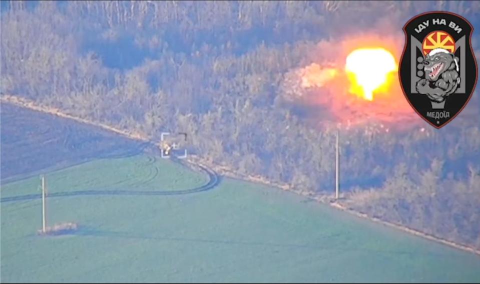 A screenshot from the video of an explosion in a forested area.