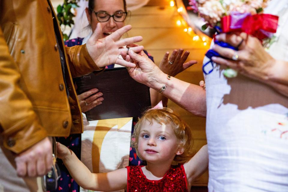 Tucker Stevenson and Julie Stewart's daughter, Tana Stevenson, watch her parents exchange their wedding rings during Morning Star Church's Valentine's Day Weddings event on Tuesday, Feb. 14, 2023, at Little Toad Creek Brewery & Distillery.