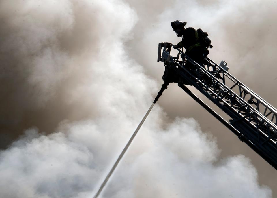 A Stockton firefighter operates a water cannon on a ladder truck while battling a blaze that gutted a commercial building on Hunter and Fremont Streets in downtown Stockton on Thursday, Sept. 15, 2022.