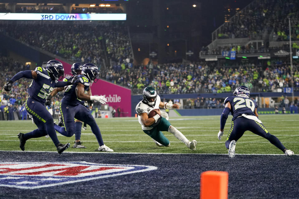 Philadelphia Eagles quarterback Jalen Hurts, center, scores on a touchdown run as a host of Seattle Seahawks players try to stop him during the first half of an NFL football game, Monday, Dec. 18, 2023, in Seattle. (AP Photo/Lindsey Wasson)