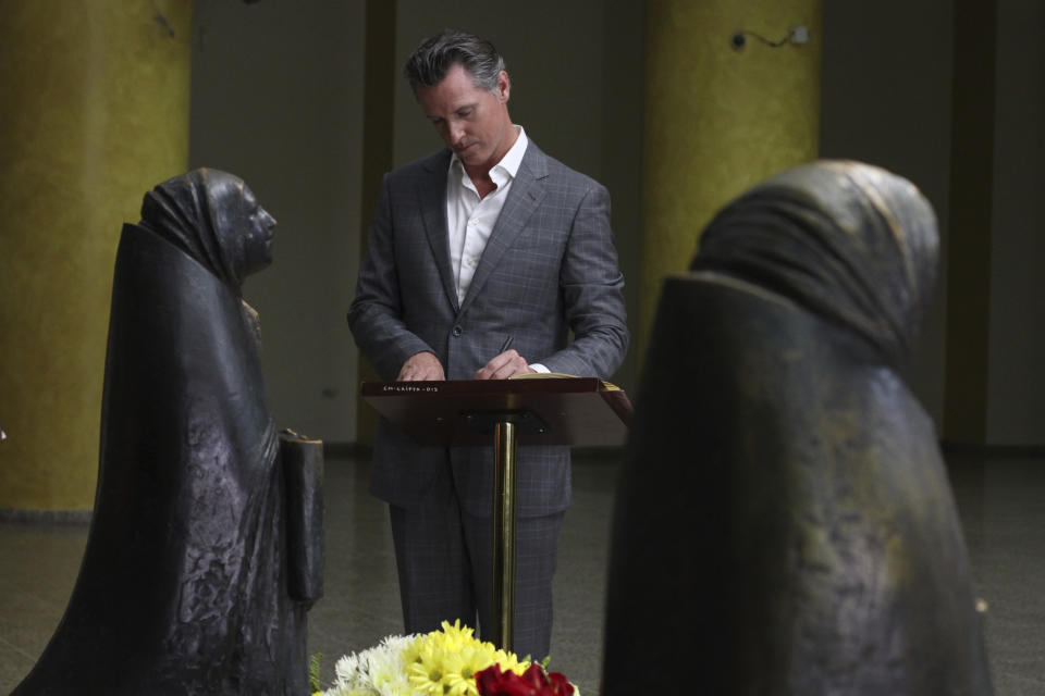 California Gov. Gavin Newsom writes a note on a book at the the tomb of Archbishop Oscar Romero at Metropolitan Cathedral in San Salvador, El Salvador, Sunday, April 7, 2019. Newsom visited the tomb of Archbishop Romero, the Salvadoran priest assassinated in 1980 due to his advocacy for human rights and the poor. (AP Photo/Salvador Melendez, Pool)