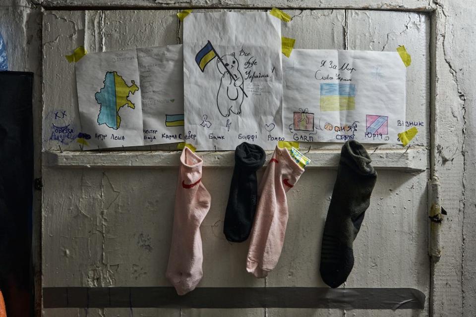 Pink and black "gift socks" with small gifts and cards from children, nailed underneath children's drawings at the entrance to the military residence on December 24, 2023 in Bakhmut Region, Ukraine.