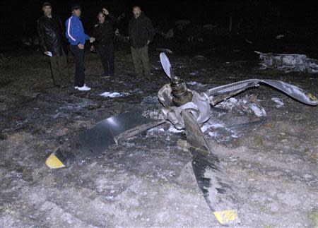 People gather near the wreckage of a Libyan military plane in Grombalia town, south of Tunis, February 21, 2014. REUTERS/Stringer