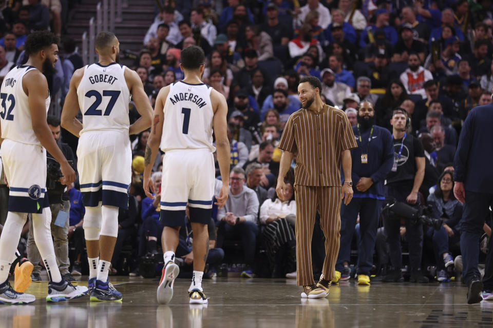 Golden State Warriors guard Stephen Curry, right, speaks with Minnesota Timberwolves center Karl-Anthony Towns (32), center Rudy Gobert (27) and forward Kyle Anderson (1) during the second half of an in-season NBA tournament basketball game in San Francisco, Tuesday, Nov. 14, 2023. (AP Photo/Jed Jacobsohn)