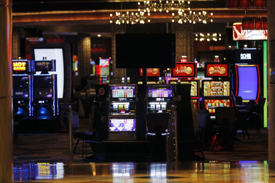 Brightly lit slot machines beckon players who cannot enter the closed gaming venues on the tribal lands of the Mississippi Band of Choctaw Indians in Philadelphia, Miss., Tuesday, July 21, 2020. The seriousness of COVID-19 and its effect on the tribe, are highlighted by the continued closure of the gaming venues and their hotels and the widely attended water park. Around 1,000 people have tested positive for the virus, including the tribal chief. More than 70 have died. (AP Photo/Rogelio V. Solis)