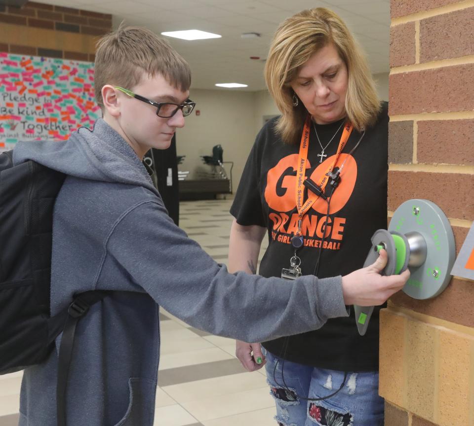 Keith Carlson unlocks his cellphone from a Yondr pouch at the end of the school day at Ellet Community Learning Center in Akron, Ohio, while safety team member Luan Haas supervises.