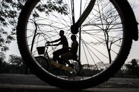 A couple rides a bicycle at a park in Bangkok February 11, 2015. REUTERS/Athit Perawongmetha