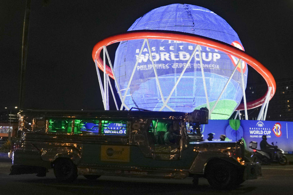 A vehicle passes a giant FIBA Basketball World Cup themed display near one of the venues at the Mall of Asia Arena Thursday, Aug. 17, 2023, in Pasay city Philippines. Basketball's World Cup starts on Friday, Aug. 25, spread out over three nations — the Philippines, Japan and Indonesia. It'll be centered in Manila. (AP Photo/Aaron Favila)