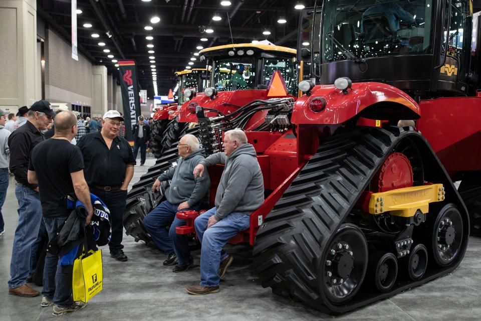 Farmers hang out chatting on the back of a Versatile 570 delt track at the National Farm Machinery Show at the Kentucky Expo Center on Feb. 12, 2020. 