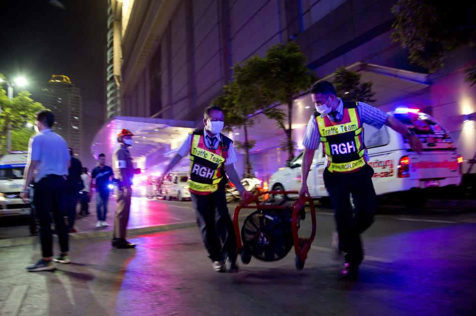 Traffic guards carry an air-blower used to remove smoke from the Central World mall in Bangkok, Thailand, Wednesday, April 10, 2019. The fire had broken out in the Central World mall complex in Thailand's capital, with reports from emergency services saying it has caused a number of fatalities. (AP Photo/Gemunu Amarasinghe)