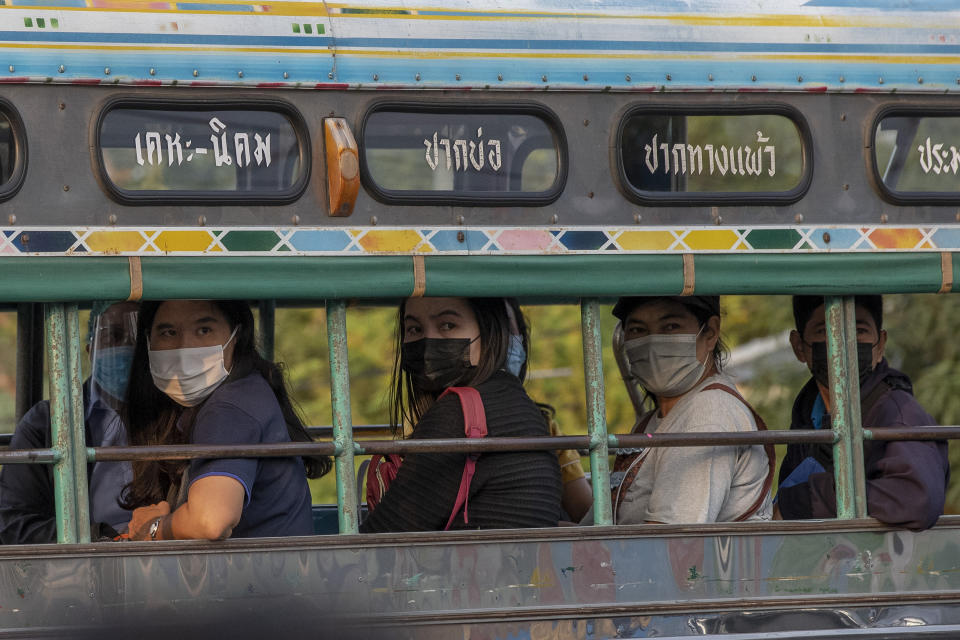 Migrant workers watch as other migrant workers and their families are carried in trucks to a field hospital for COVID-19 patents in Samut Sakhon, South of Bangkok, Thailand, Monday, Jan. 4, 2021. For much of 2020, Thailand had the coronavirus under control. After a strict nationwide lockdown in April and May, the number of new local infections dropped to zero, where they remained for the next six months. However, a new outbreak discovered in mid-December threatens to put Thailand back where it was in the toughest days of early 2020 (AP Photo/Gemunu Amarasinghe)