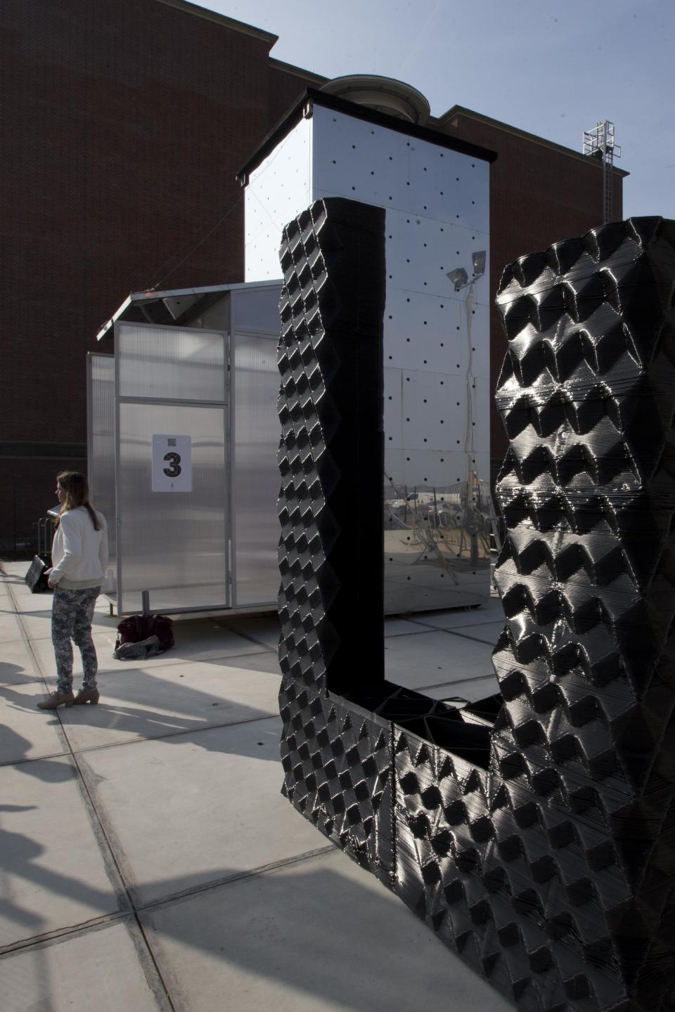 A 3D printer, rear, and part of a printed canal house, foreground, are lit by the sunlight in Amsterdam, Netherlands, Thursday, March 13, 2014. Dutch architecture firm Dus has embarked on a project to build a 21st-century version of a classic Amsterdam canal house, printing it out piece by piece with an oversized 3-D printer, and then slotting them together like oversized Lego blocks. The goal is to discover and share the potential uses of 3-D printing in construction by creating new materials, trying out designs and testing building techniques. (AP Photo/Peter Dejong)