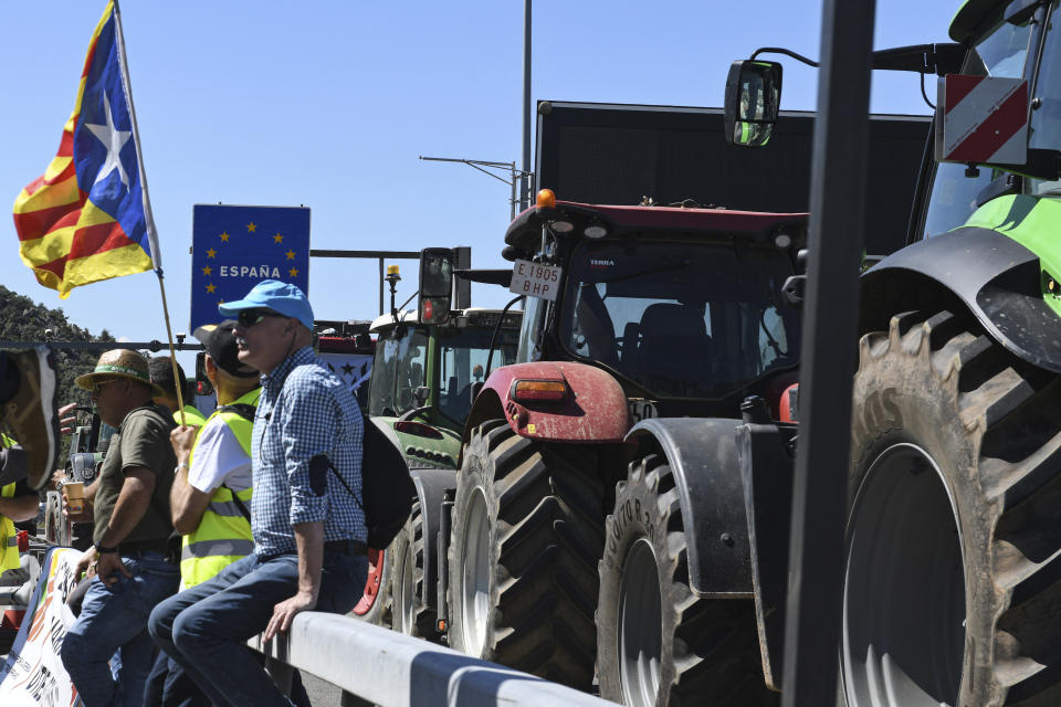 A Catalonia Independence flag flies as tractor drivers sit by their tractors blocking the Le Perthus French-Spanish border Monday June 3, 2024. Farmers from Catalonia are blocking the major road route between Spain and France in northern Catalonia complaining that they are being put out of business by restrictions and need more subsidies. (Gloria Sanchez/Europa Press via AP)