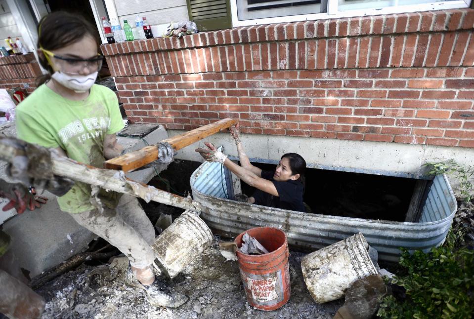 Neighbor Reznickek passes a piece of wood from the ruined basement to McCarthy as they work to clean up the flood damage in McCarthy's home in Boulder, Colorado