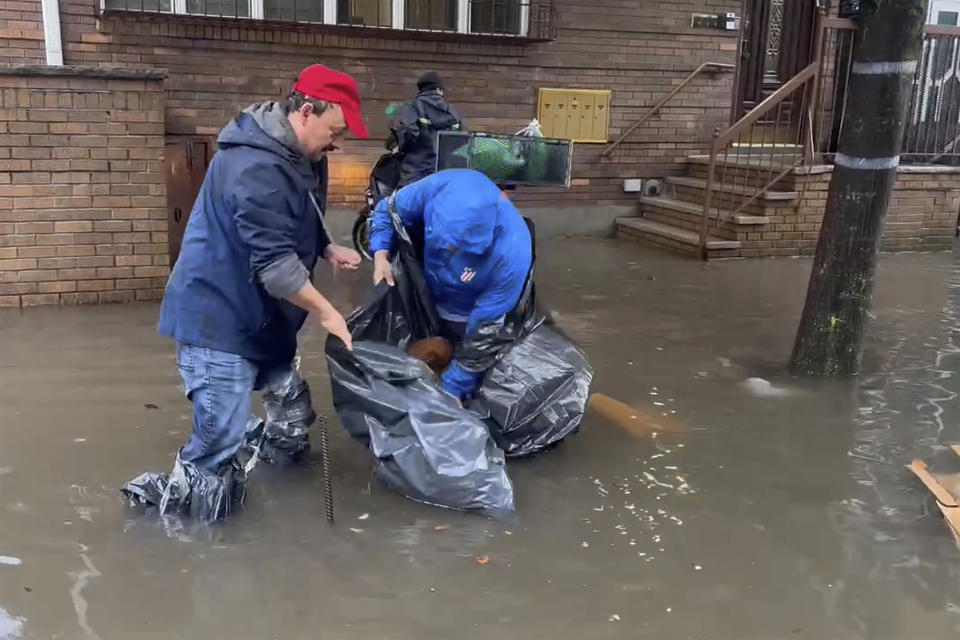 In this photo taken from video, work in flood waters to clear drains on a street, Friday, Sept. 29, 2023, in the Brooklyn borough of New York. A potent rush-hour rainstorm has swamped the New York metropolitan area. The deluge Friday shut down swaths of the subway system, flooded some streets and highways, and cut off access to at least one terminal at LaGuardia Airport. (AP Photo/Jake Offenhartz)