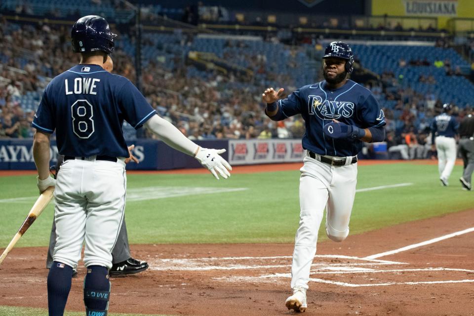 Tampa Bay Rays' Manuel Margot, right, heads to the dugout and is congratulated by Brandon Lowe after scoring during the first inning at Tropicana Field in St. Petersburg, Florida, on Thursday, Sept. 16, 2021.