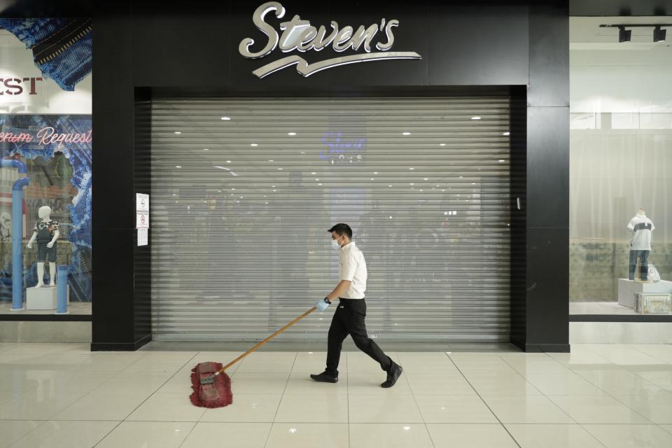 A worker sweeps the Multiplaza Mall as shops prepare to open later in the morning, in Panama City, Monday, Aug. 17, 2020. After nearly five months of quarantine, on Monday Panama is starting a partial reopening of the economy, with barbers, beauty salons, retail and car lots opening their doors, in an effort to revive the economy while preparing for another possible spike in coronavirus cases. (AP Photo/Arnulfo Franco)