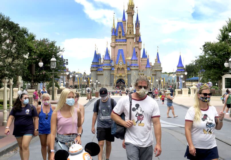 Guests wear masks as required to attend the official reopening day of the Magic Kingdom at Walt Disney World in Lake Buena Vista, Fla., Saturday, July 11, 2020. Disney reopened two Florida parks, the Magic Kingdom and Animal Kingdom, Saturday, with limited capacity and safety protocols in place in response to the coronavirus pandemic. (Joe Burbank/Orlando Sentinel via AP)