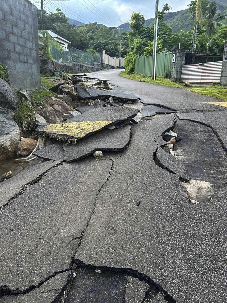 Cracks along a road in the aftermath of a massive explosion at an industrial area on the main island in Mahe, Seychelles, Thursday, Dec. 7, 2023. Authorities in Seychelles declared a state of emergency Thursday after a blast at an explosives store caused “massive damage” in an industrial area also facing flooding amid heavy rainfall, according to the presidency. The blast happened on Wednesday night in the Providence area of Mahe, the largest and most populous island of the Seychelles. (AP Photo/Emilie Chetty)