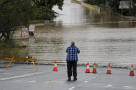 A man takes a photo of flooded street at Windsor on the outskirts of Sydney, Australia, Tuesday, July 5, 2022. Hundreds of homes have been inundated in and around Australia's largest city in a flood emergency that was impacting 50,000 people, officials said Tuesday. (AP Photo/Mark Baker)