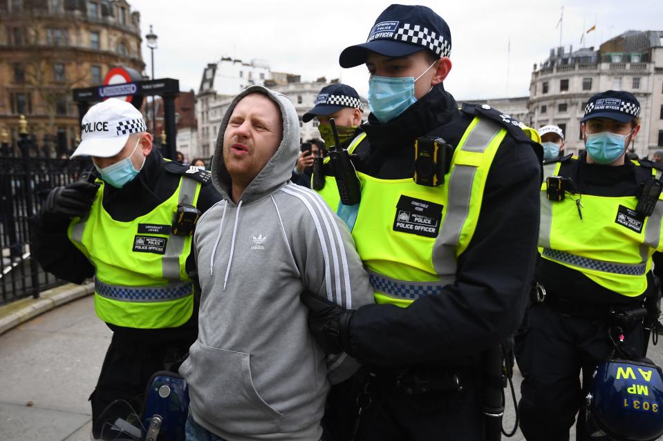 Police detain a man as people take part in an anti-lockdown protest in Trafalgar SquarePA