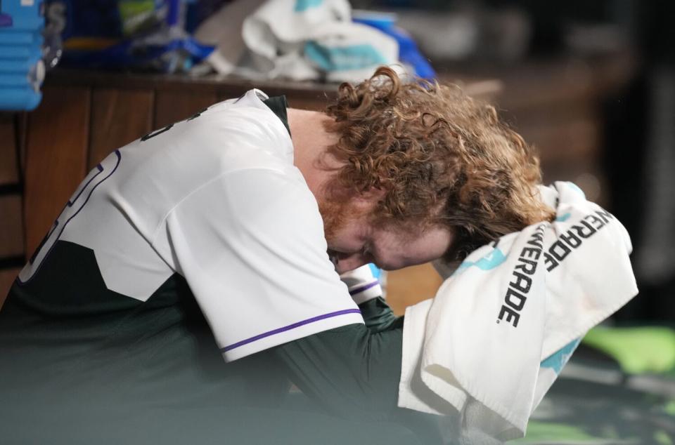 Rockies relief pitcher Noah Davis bows his head as he sits in the dugout after giving up early in the sixth inning