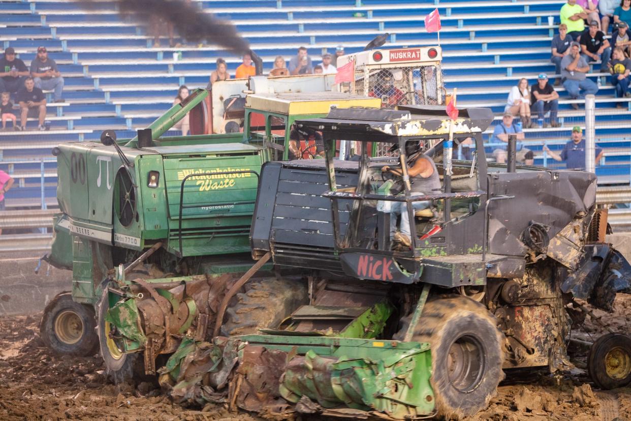 Two farm combines dance around each other while a third moves in for a collision during the combine demolition derby event at the 75th Annual Monroe County Fair.