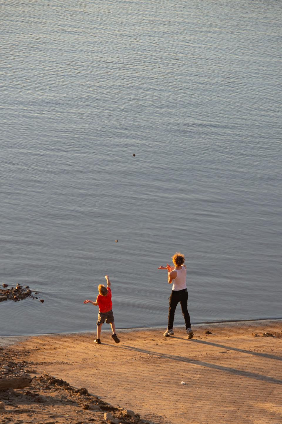 Kolby Caine, 9, skips rocks with Hunter Curtis, 15, on the banks of the Ohio River during Tri-Fest in Henderson, Ky., Friday evening, April 14, 2023.