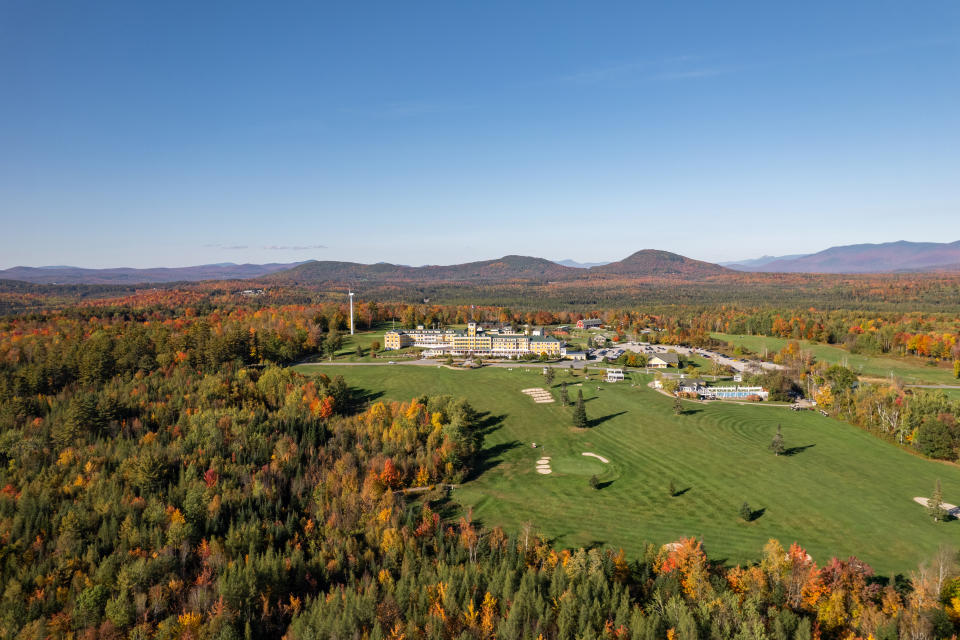 An aerial view of the Mountain View Grand Resort & Spa in New Hampshire during autumn with trees turning red and orange from the leaves