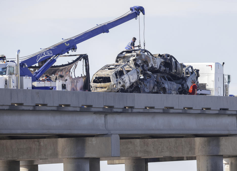 Workers remove heavily damaged vehicles from Interstate 55 near Manchac, La., Monday, Oct. 23, 2023. A “superfog” of smoke from south Louisiana marsh fires and dense morning fog caused multiple traffic crashes involving scores of cars Monday, turning I-55 near New Orleans into a narrow junkyard of mangled cars and trucks, some of them burning. (Brett Duke/The Times-Picayune/The New Orleans Advocate via AP)