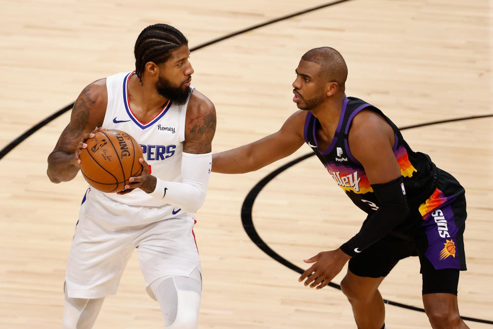 Paul George with the ball in his hands looking past Chris Paul who is guarding him.