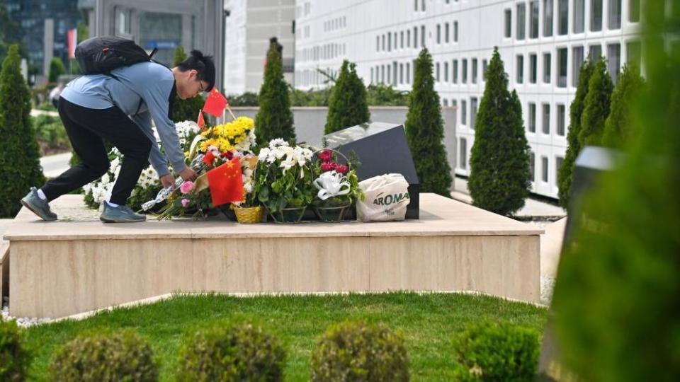 A visitor places flowers at a monument on the site of a former Chinese embassy ahead of China's President Xi Jinping's state visit on Tuesday, May 7, 2024, in Belgrade, Serbia