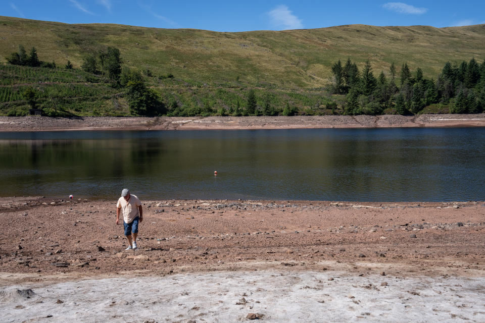 MERTHYR TYDFIL, WALES - AUGUST 12: A man walks on the dried shore of the Beacons Reservoir as it lies low during the current heat wave, on August 12, 2022 in Merthyr Tydfil, Wales. Areas of the UK were declared to be in drought today as the country's Met Office continues its amber extreme heat warning for parts of England and Wales. (Photo by Carl Court/Getty Images)