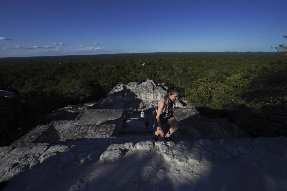 A woman climbs up a pyramid in the Calakmul Biosphere Reserve at the Calakmul Mayan ruins in the Yucatan Peninsula of Mexico on Tuesday, Jan. 10, 2023. The Maya Train, which will stop nearby, is intended to drive economic development to some of the country's poorest areas, in part by bringing up to three million tourists each year. (AP Photo/Marco Ugarte)