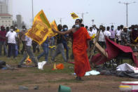 A Buddhist monk joins other government supporters in vandalizing the site of anti-government protests outside the president's office in Colombo, Sri Lanka, Monday, May 9, 2022. An official says Sri Lankan Prime Minister Mahinda Rajapaksa has resigned following weeks of protests demanding that he and his brother, the president, step down over the country’s worst economic crisis in decades. (AP Photo/Eranga Jayawardena)