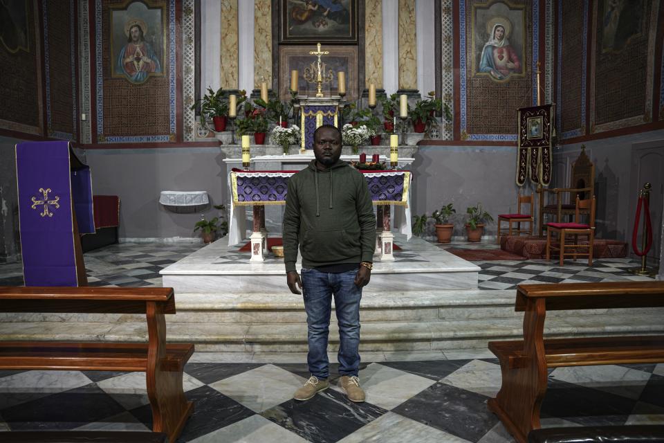 Christian Tango Muyaka, a 30-year-old asylum-seeker from Congo, poses for a photograph inside a Catholic church in Mytilene port, on the northeastern Aegean island of Lesbos, Greece, Monday, Nov. 29, 2021. Muyaka will attend a Sunday service held by the pope at a new migrant camp on Lesbos. Pope Francis is heading back to the Greek island of Lesbos to meet migrants and asylum seekers for the second time in five years. (AP Photo/Panagiotis Balaskas)