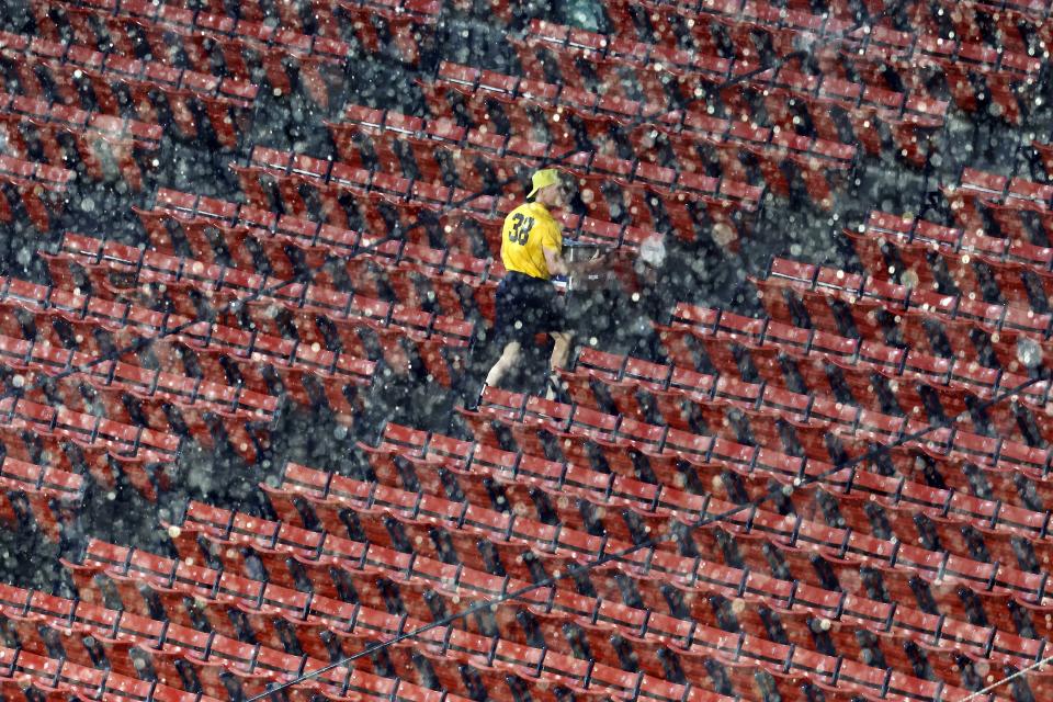 A vendor at Fenway Park walks through empty stands during a rain delay before a baseball game between the Boston Red Sox and the Tampa Bay Rays, Friday, June 2, 2023, in Boston. (AP Photo/Michael Dwyer)