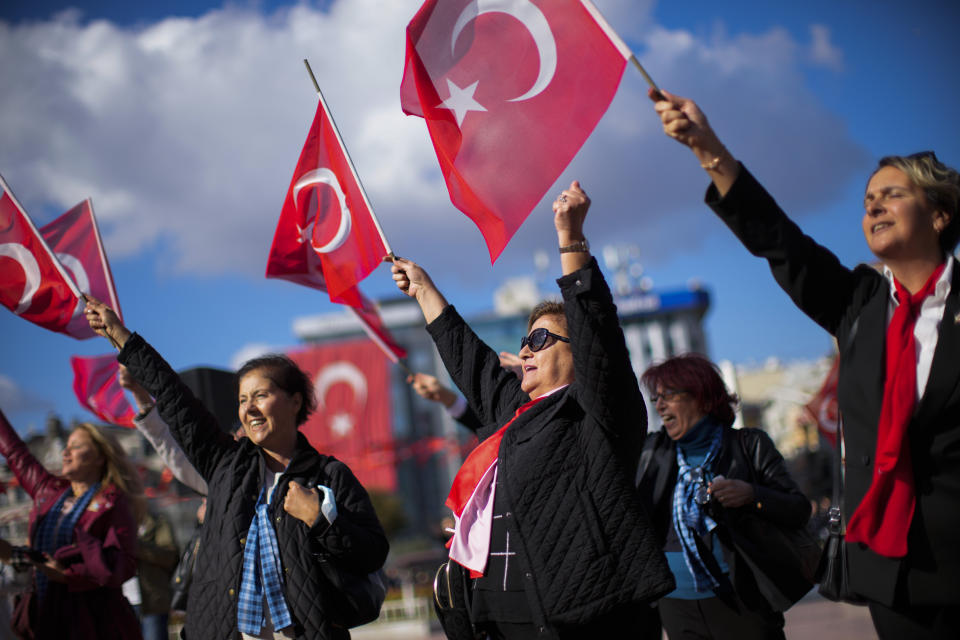 People wave Turkish flags as they listen a military music band performing at Taksim square in Istanbul, Turkey, Friday, Oct. 28, 2022. Turkish President Recep Tayyip Erdogan on Friday laid out his vision for Turkey in the next century, promising a new constitution that would guarantee the rights and freedoms of citizens. (AP Photo/Francisco Seco)