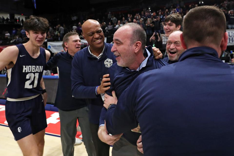 Hoban basketball coach TK Griffth, center, is mobbed by his son, No. 21 Andrew Griffith, and staff members, from left to right, Mike MacDonald, Stephen White, Hank Inman and Tim Lucey after beating Pickerington Central to win the OHSAA Division I state championship, Sunday, March 19, 2023, in Dayton.