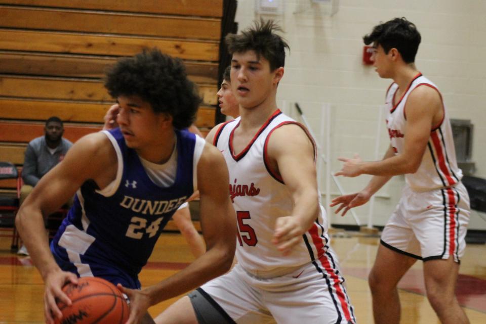 Dundee's Braiden Whitaker looks to pass after being stopped by Monroe defender Adam Nobozny. Dundee pulled away in the fourth quarter to beat Monroe 55-41 Wednesday night.