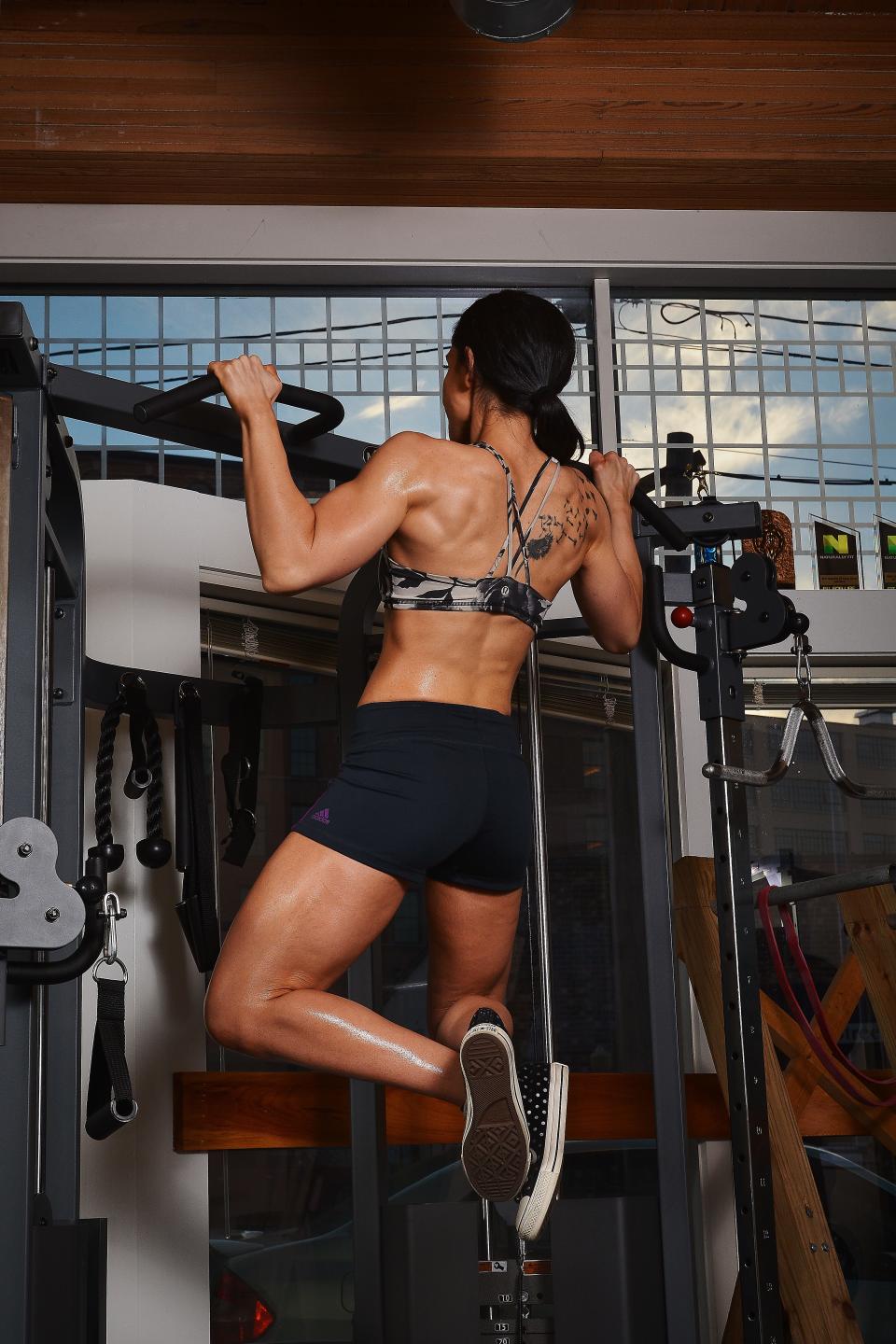 Athlete and bodybuilder Dani Taylor performing a pull-up at the gym