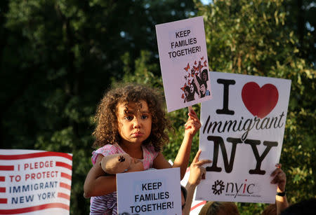 FILE PHOTO: A girl sitting on the shoulders of her father holds a sign reading "Keep Families Together" at a protest against U.S. President Donald Trump's proposed end of the DACA program that protects immigrant children from deportation in New York City, U.S., August 30, 2017. REUTERS/Joe Penney/File Photo