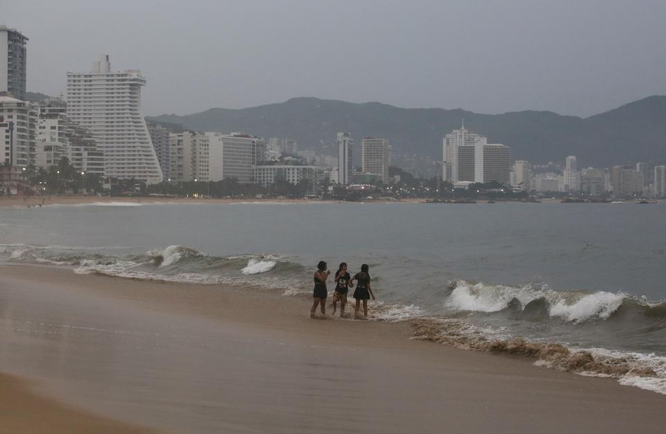 People stand on a beach as Hurricane Otis barrels towards Acapulco (REUTERS)