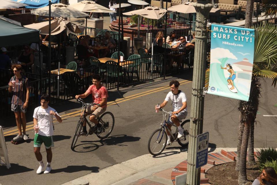 Bikers pass "Masks Up, Surf City" banners in Huntington Beach.