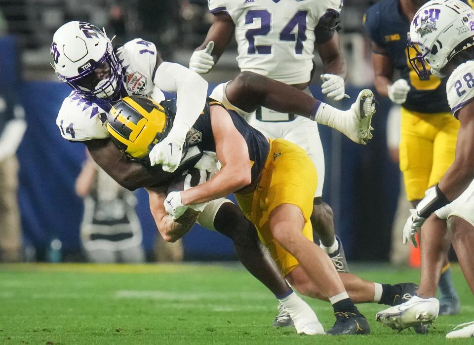 Horned Frogs safety Abe Camara (14) tackles Michigan Wolverines receiver Roman Wilson.