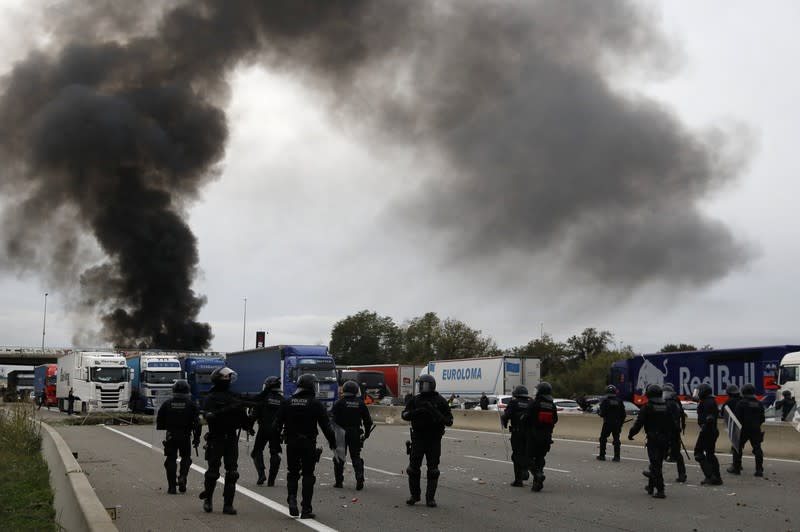 Police officers walk as members of Catalan protest group Democratic Tsunami block the AP-7 highway in Girona