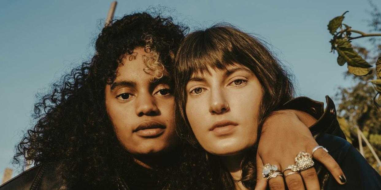 portrait of female friends with arm around outdoors on sunny day