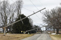 Downed power lines lean close to the street in Evansville, Wis., Friday, Feb. 9, 2024. The first tornado ever recorded in Wisconsin in the usually frigid month of February came on a day that broke records for warmth, the type of severe weather normally seen in the late spring and summer. (Amber Arnold/Wisconsin State Journal via AP)