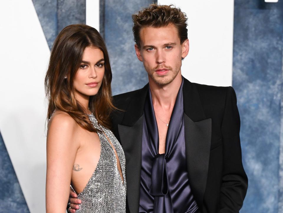 Kaia Gerber in a silver dress and Austin Butler in a black suit posing